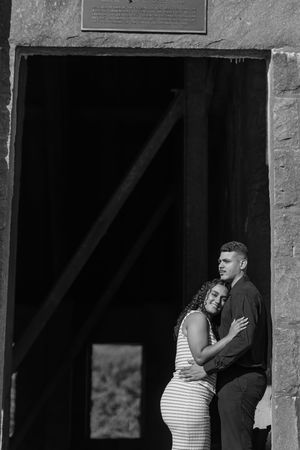 Black and white photo of people embracing in a doorway, with dramatic shadows and light creating a moody atmosphere.