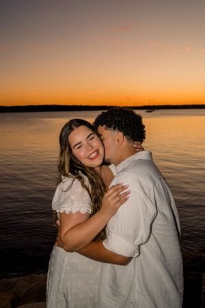 A couple shares intimate moments at sunset by the water's edge in a romantic photoshoot series.