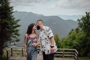 A romantic moment shared between a couple on a mountain viewpoint deck with scenic mountain views.