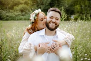 A tender moment shared between a couple in a sunny meadow with wildflowers.