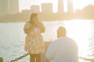 A couple sits together by the water during golden hour, creating a romantic silhouette against the sunset.