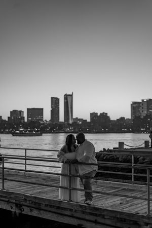 A romantic couple silhouetted against the Boston skyline at sunset on a waterfront boardwalk in a sequence of four images.