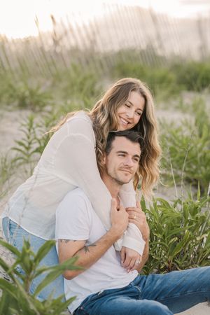 Couple sharing intimate moments while laying in tall grass on a sunny afternoon.