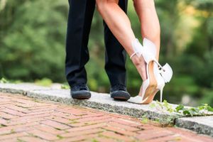 Close-up of formal shoes on a brick pathway showing a stylish couple's feet.