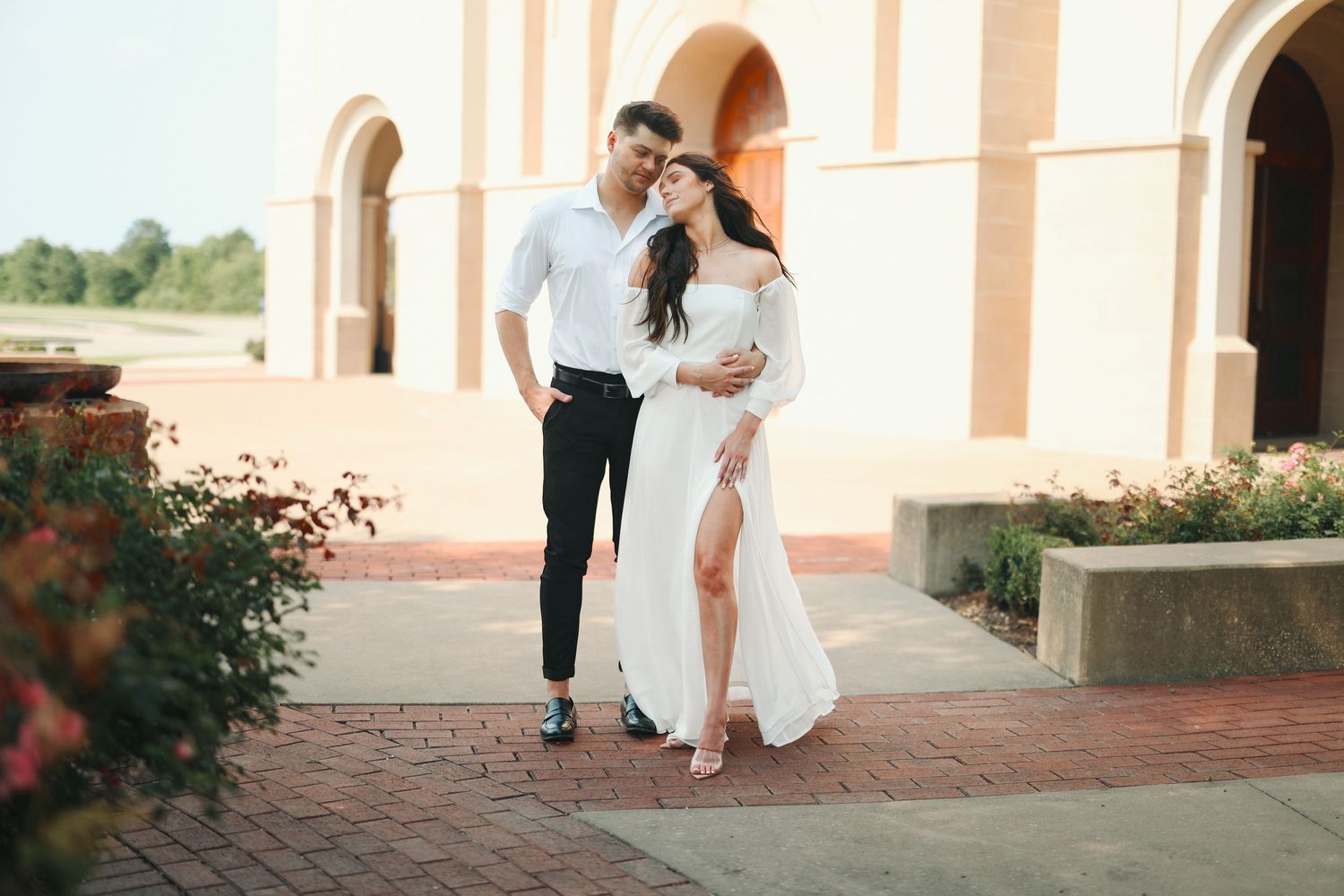a newly engaged couple embracing in front of a beautiful church