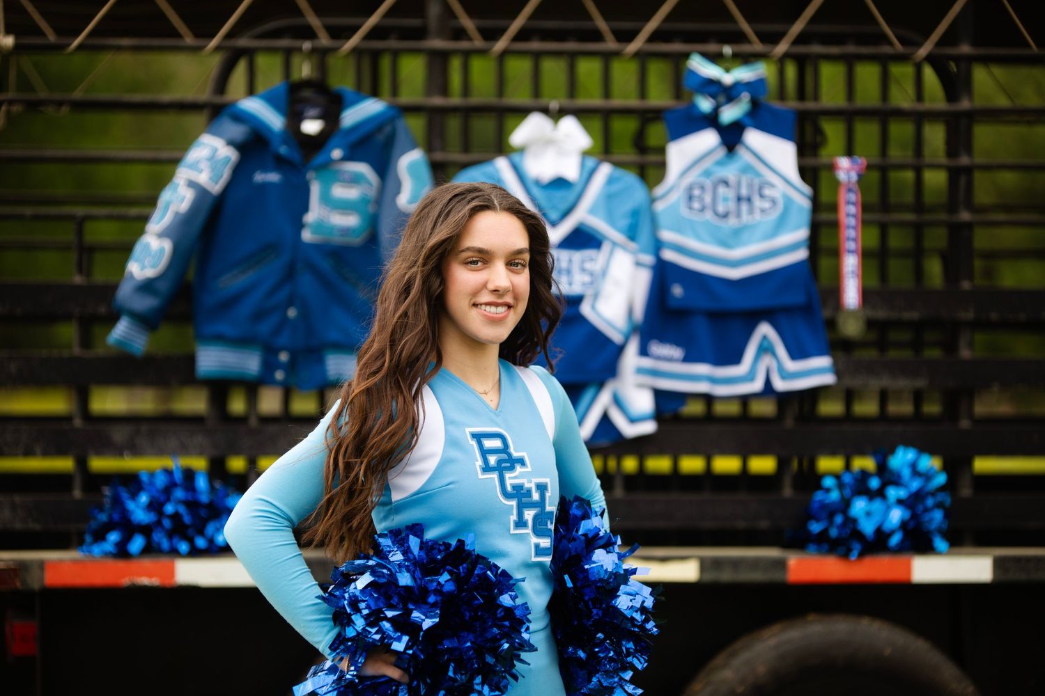 Senior graduate portrait cheerleader with varsity jackets display.
