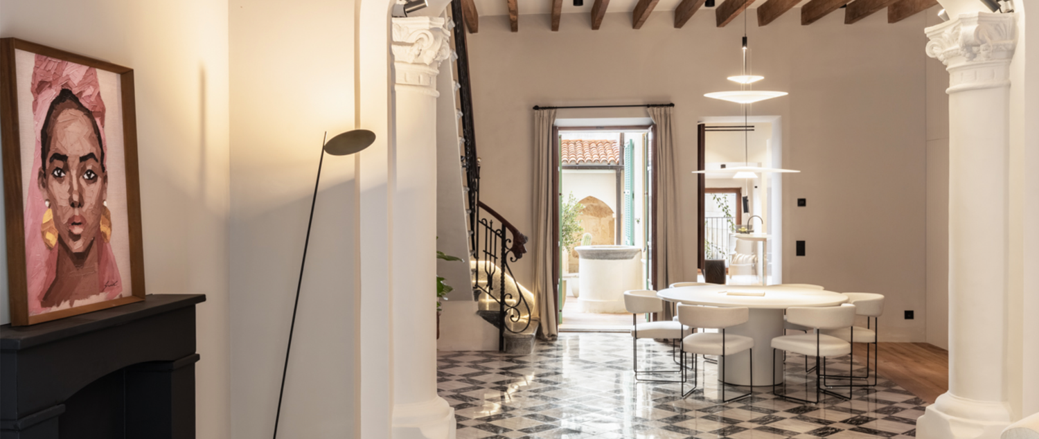 Modern apartment interior with exposed wooden beams, black and white checkered floor, and contemporary furnishings.