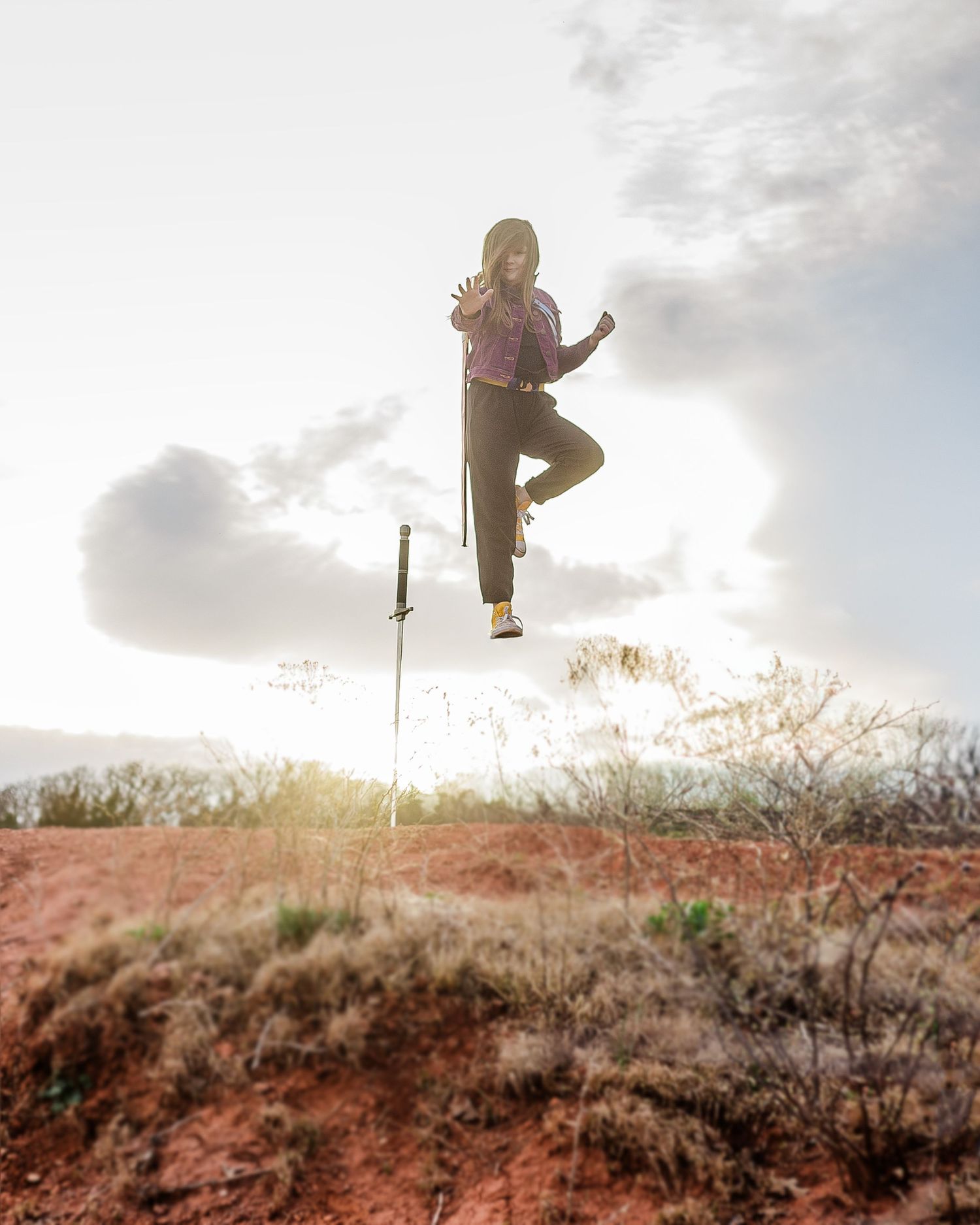 Dynamic action shot of someone leaping high in the air with a sword against a sunset sky.