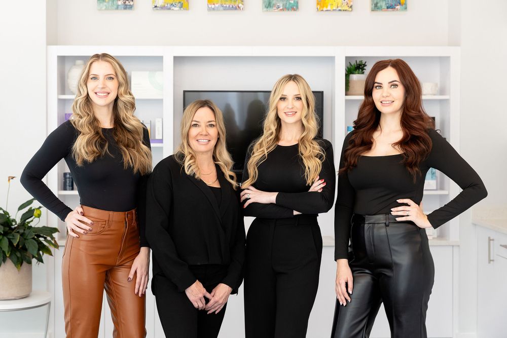 Group of professionals in black outfits posing together in modern office setting.