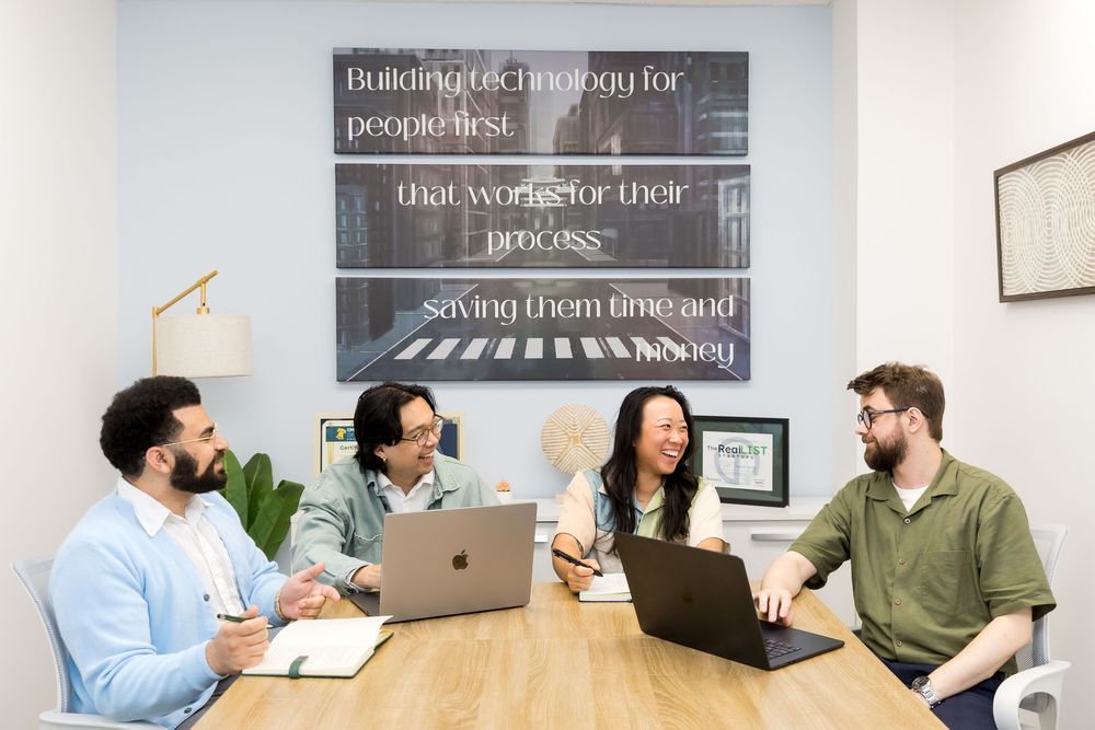 Team members collaborating and having a discussion around a conference table in a modern office space.