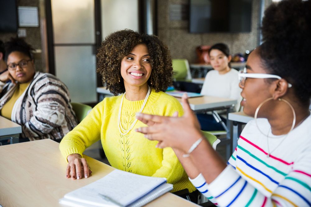 Students in a classroom engage in lively discussion while wearing protective face masks during a learning session.