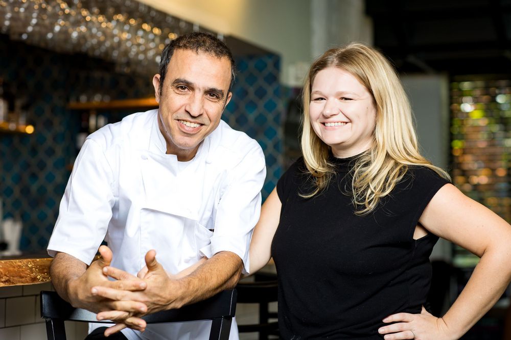 Restaurant staff interacting in a cozy dining establishment with patterned wall decor.