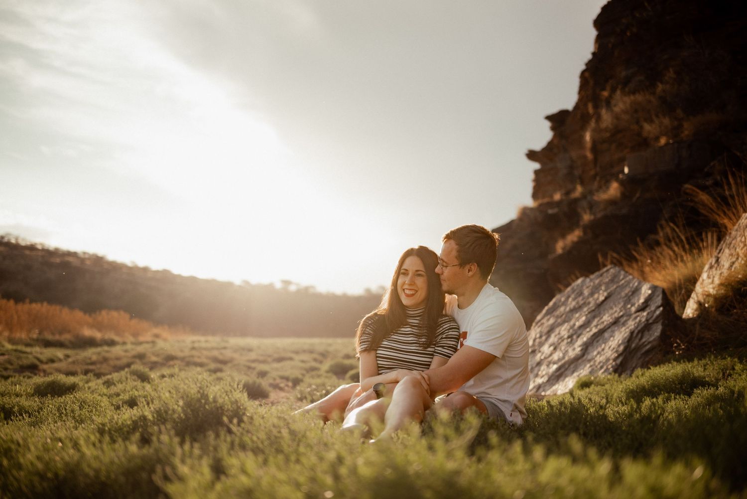 A couple enjoying a peaceful moment together near rocky cliffs at sunset.