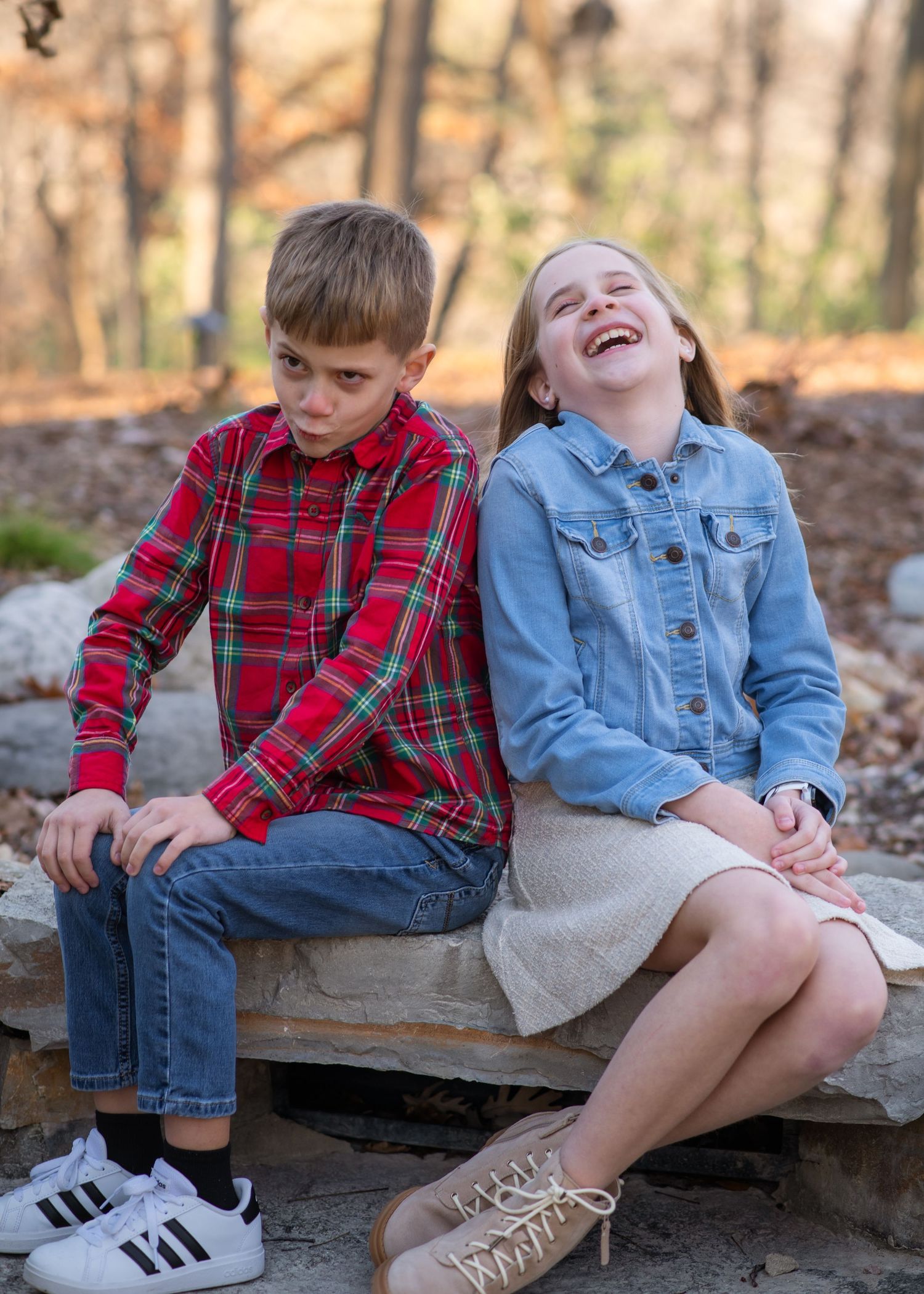 Two children sit on wooden steps outdoors sharing a candid moment together.
