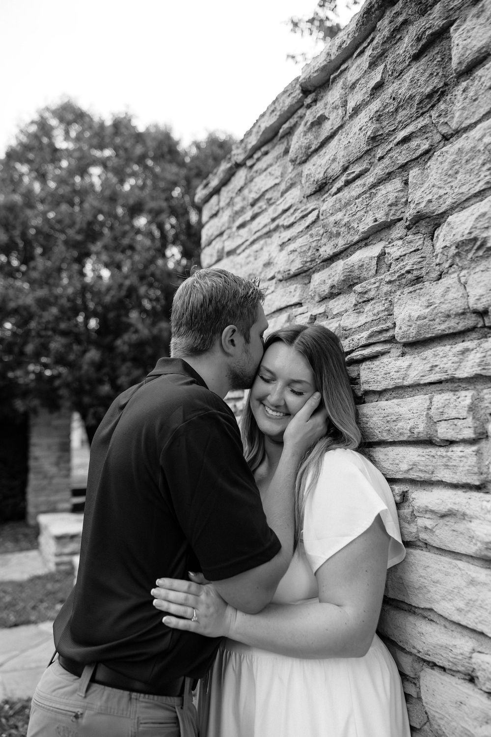 A romantic series of black and white photos showing a couple embracing against a stone wall.