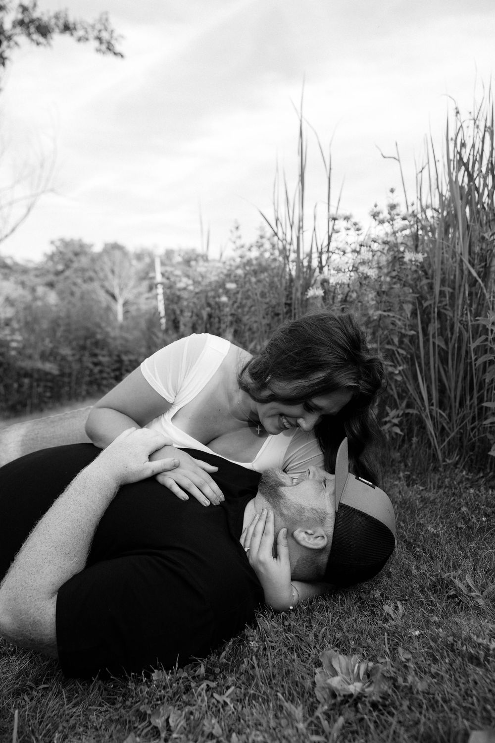 A black and white photo series showing a figure laying in grass with artistic poses against a nature backdrop.