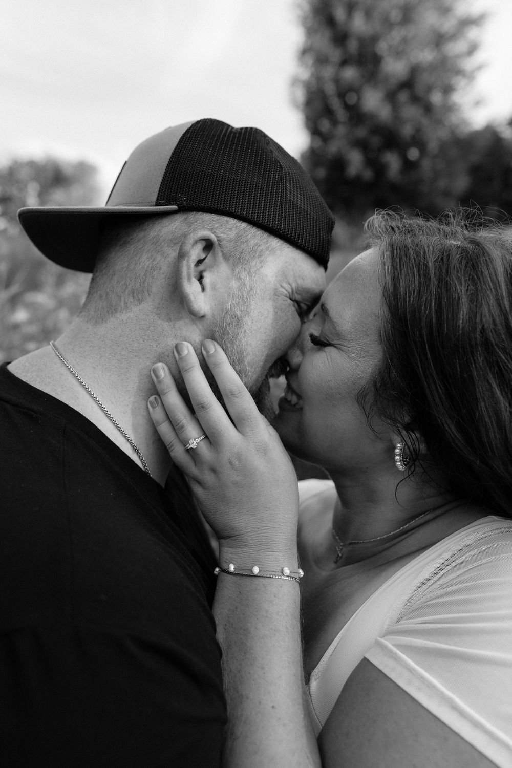 An intimate black and white portrait of a tender moment between two people in an outdoor setting.