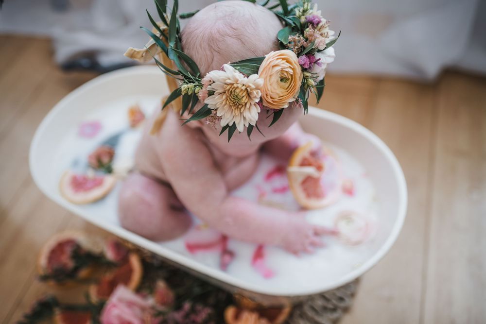Overhead view of milk bath photography setup with flowers and citrus slices.