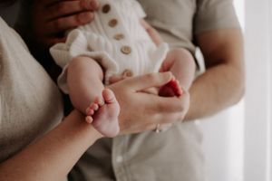 Close up of newborn baby's feet while being held in mum and dad's arms.
