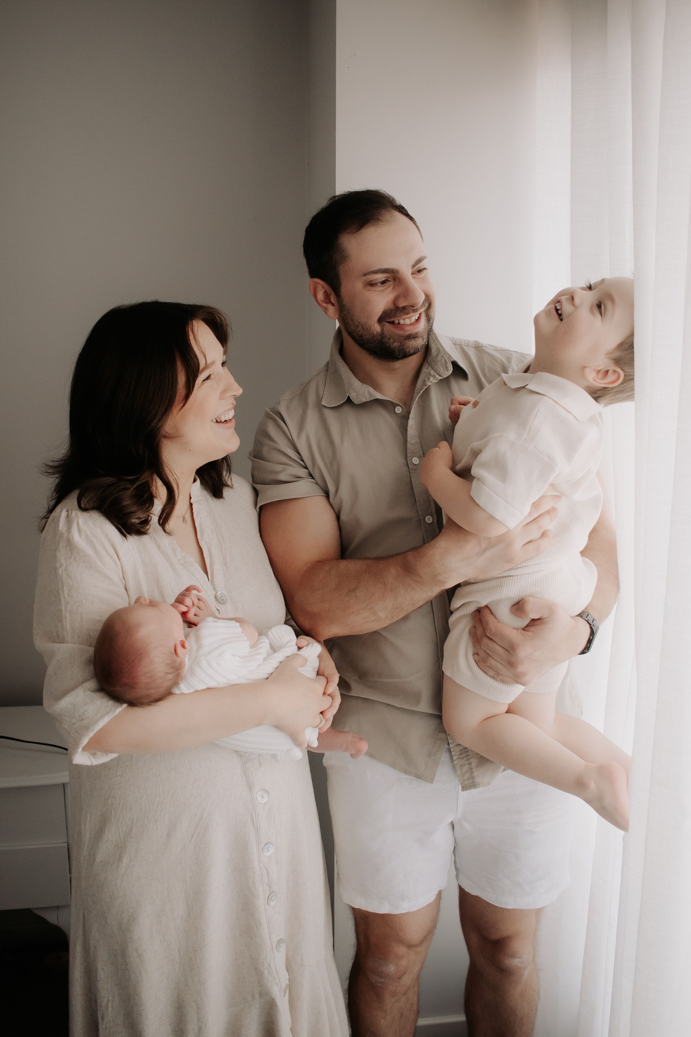 Family standing by the window laughing.