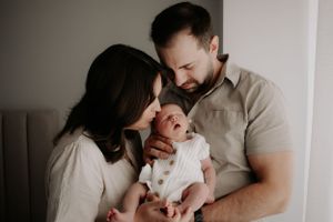 Dad holding baby while mum kisses her head.