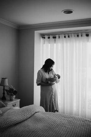Mum holding newborn by the window.
