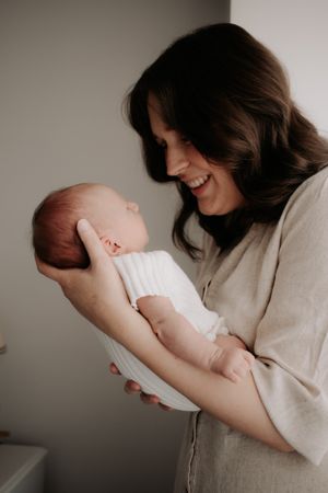 Mum holding newborn in her arms looking down at her.
