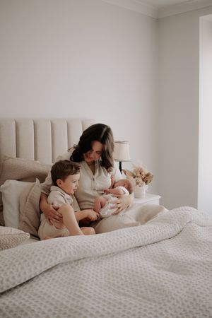 Mum sitting in the bed with her son and newborn.