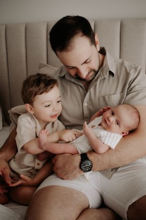 Dad sitting in the bed with his son and newborn.