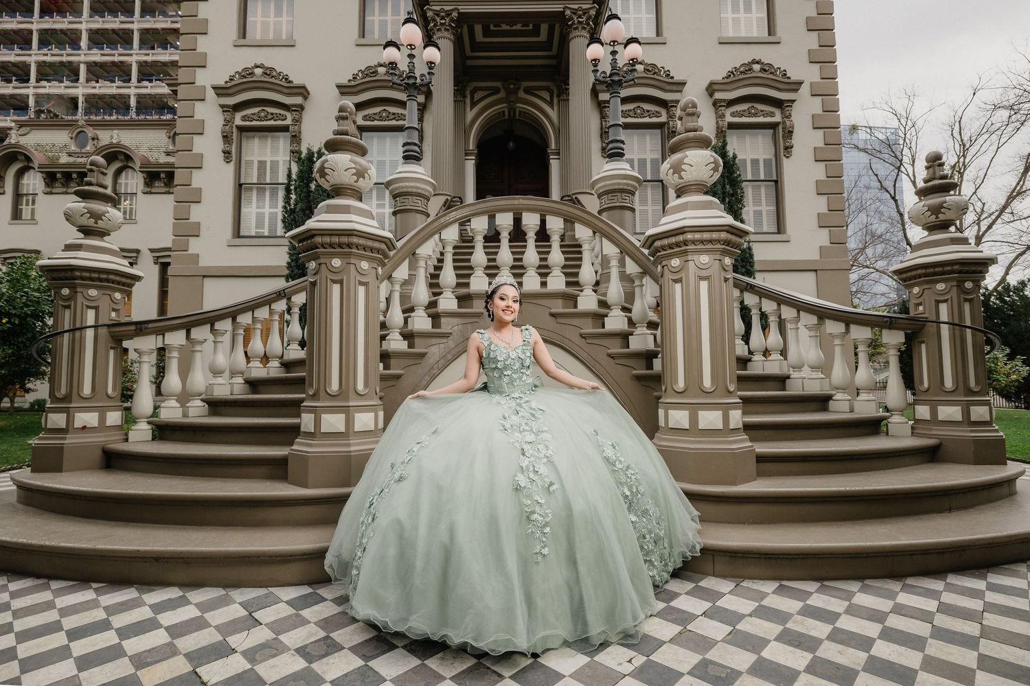 Mint green ball gown photographed on ornate stone staircase of historic building.