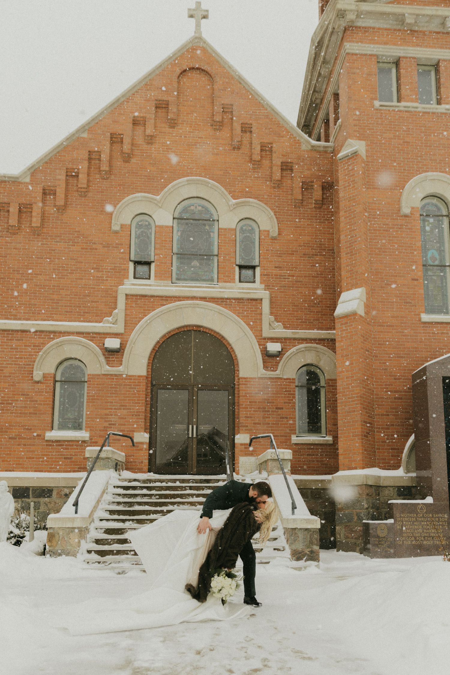 Snow covered brick church exterior with people walking in winter weather.