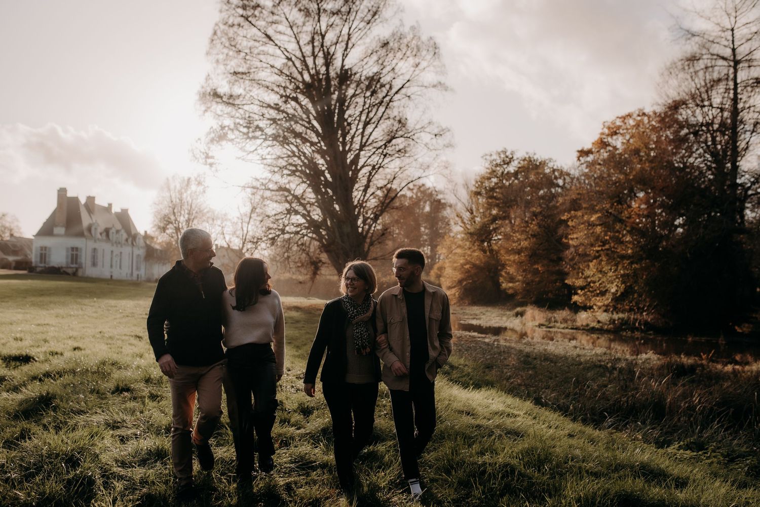 Silhouettes of group walking together at sunset with trees and house in background.