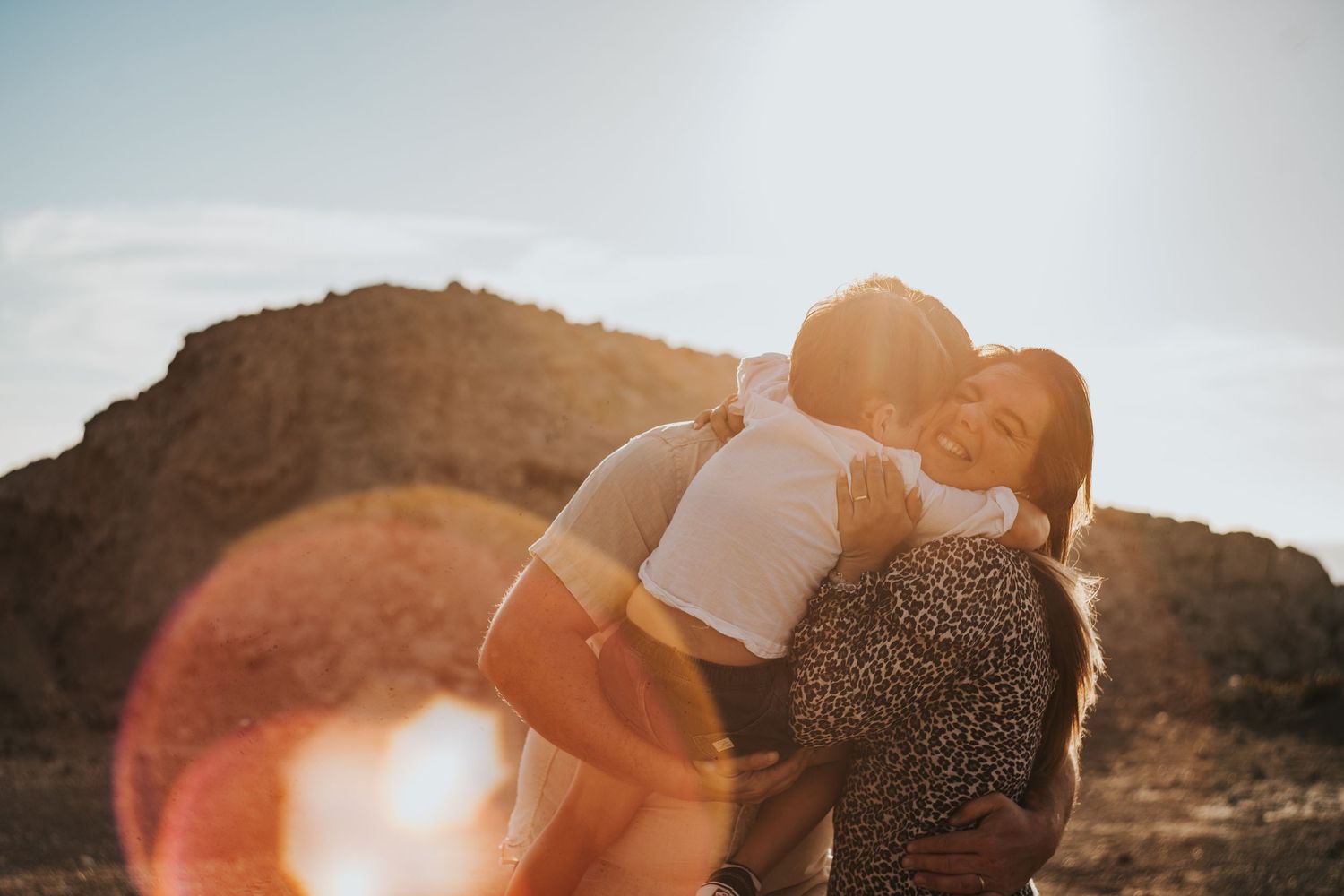 A series of photos showing a couple embracing on a beach during sunset with mountains in the background.