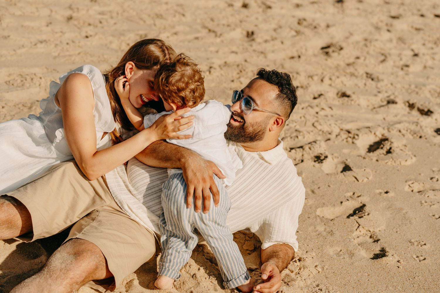 Couple sharing an intimate moment together on a sandy beach during golden hour.