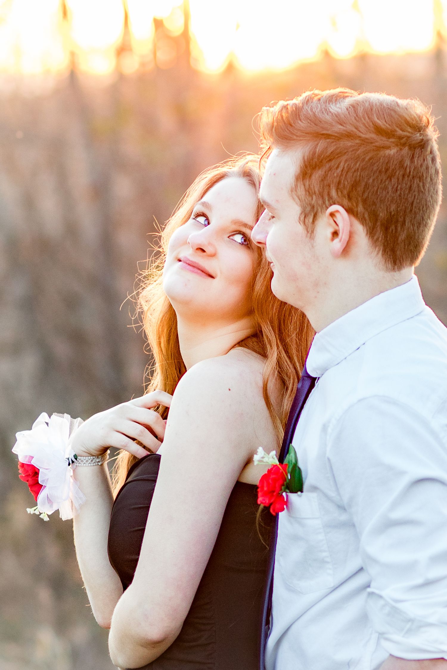 Romantic sunset portrait of a couple embracing at golden hour wearing formal attire.