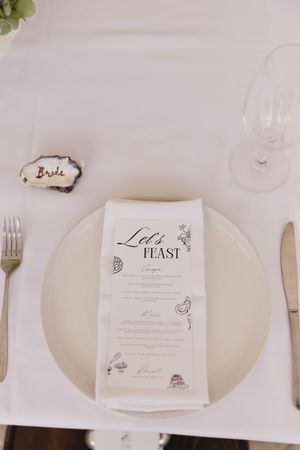 Elegant white place settings with menu cards and silverware arranged on a dining table.