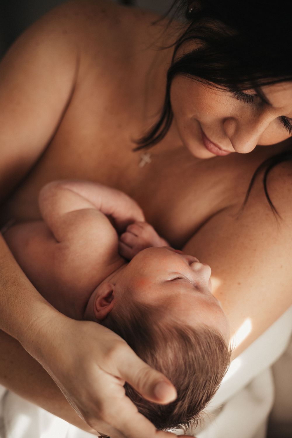 A peaceful skin-to-skin bonding moment in dramatic lighting.