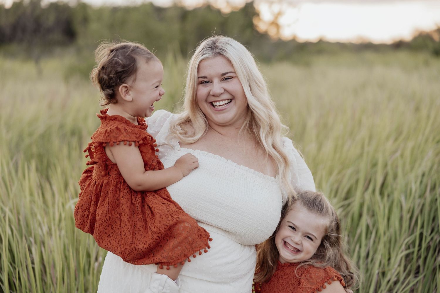 Joyful family moment captured in a sun-lit field with tall grass.