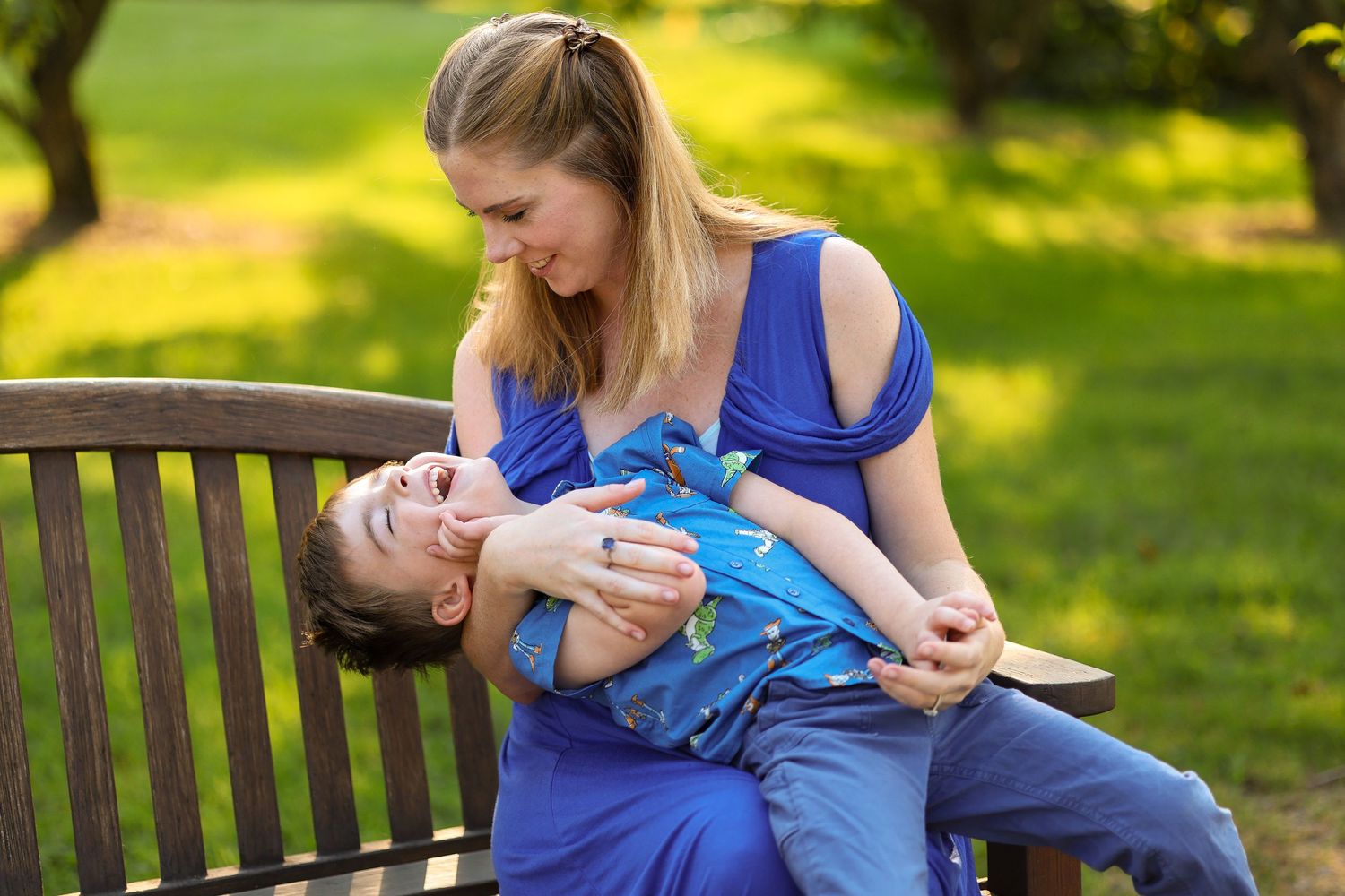 A tender moment shared between parent and child on a wooden park bench in golden sunlight.