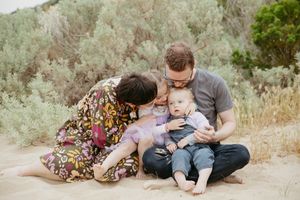 A family shares an intimate moment while sitting together on a hillside with sage brush.