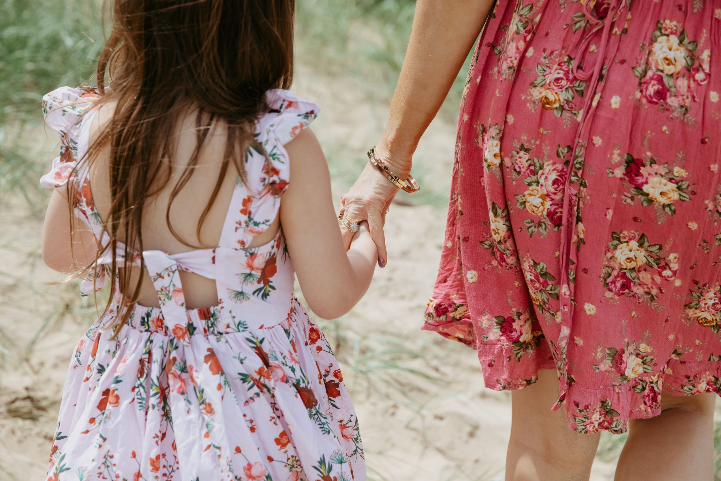 Two people wearing floral summer dresses walking together, showing details of vintage-inspired ruffled clothing.