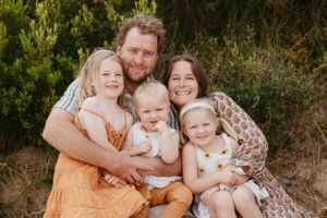 Family group snuggling close together outdoors for a portrait.