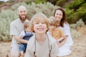 A joyful family moment captured during an outdoor photo session among coastal vegetation.