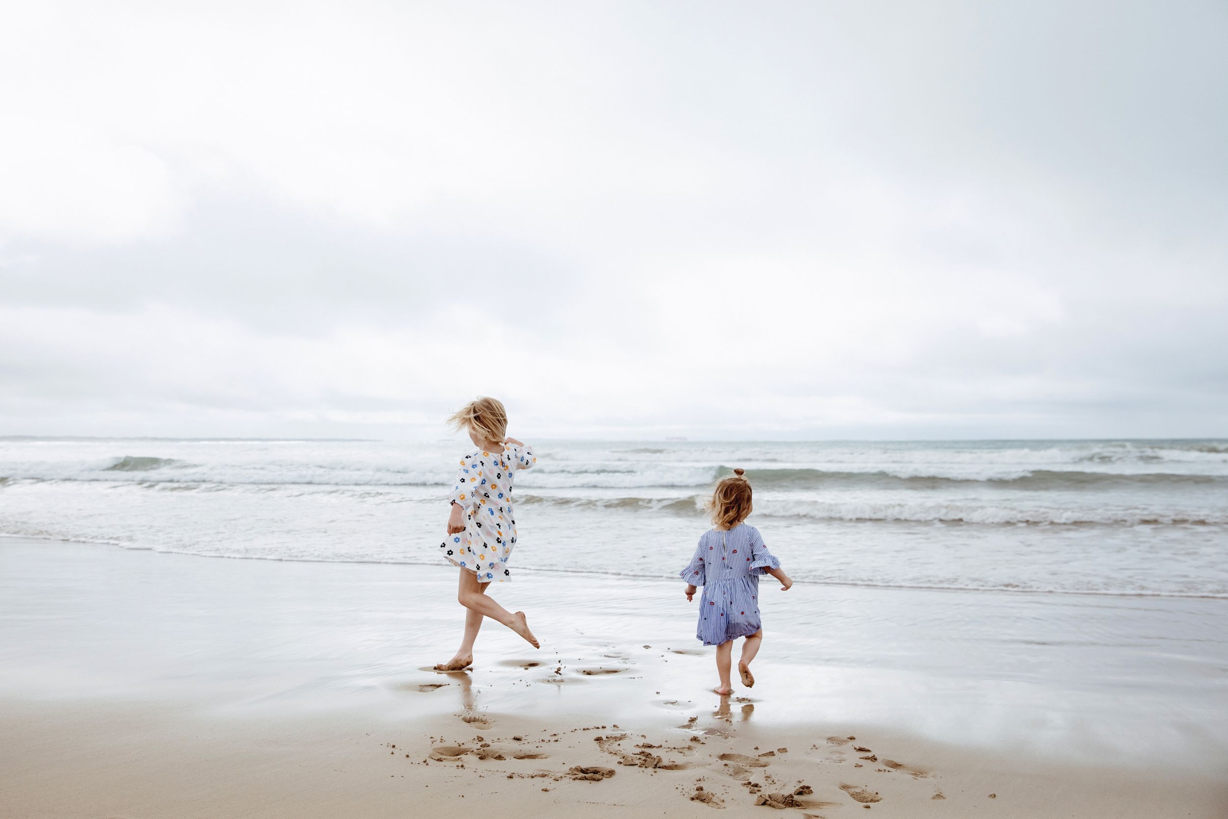 Two people playing and running together on a misty beach.