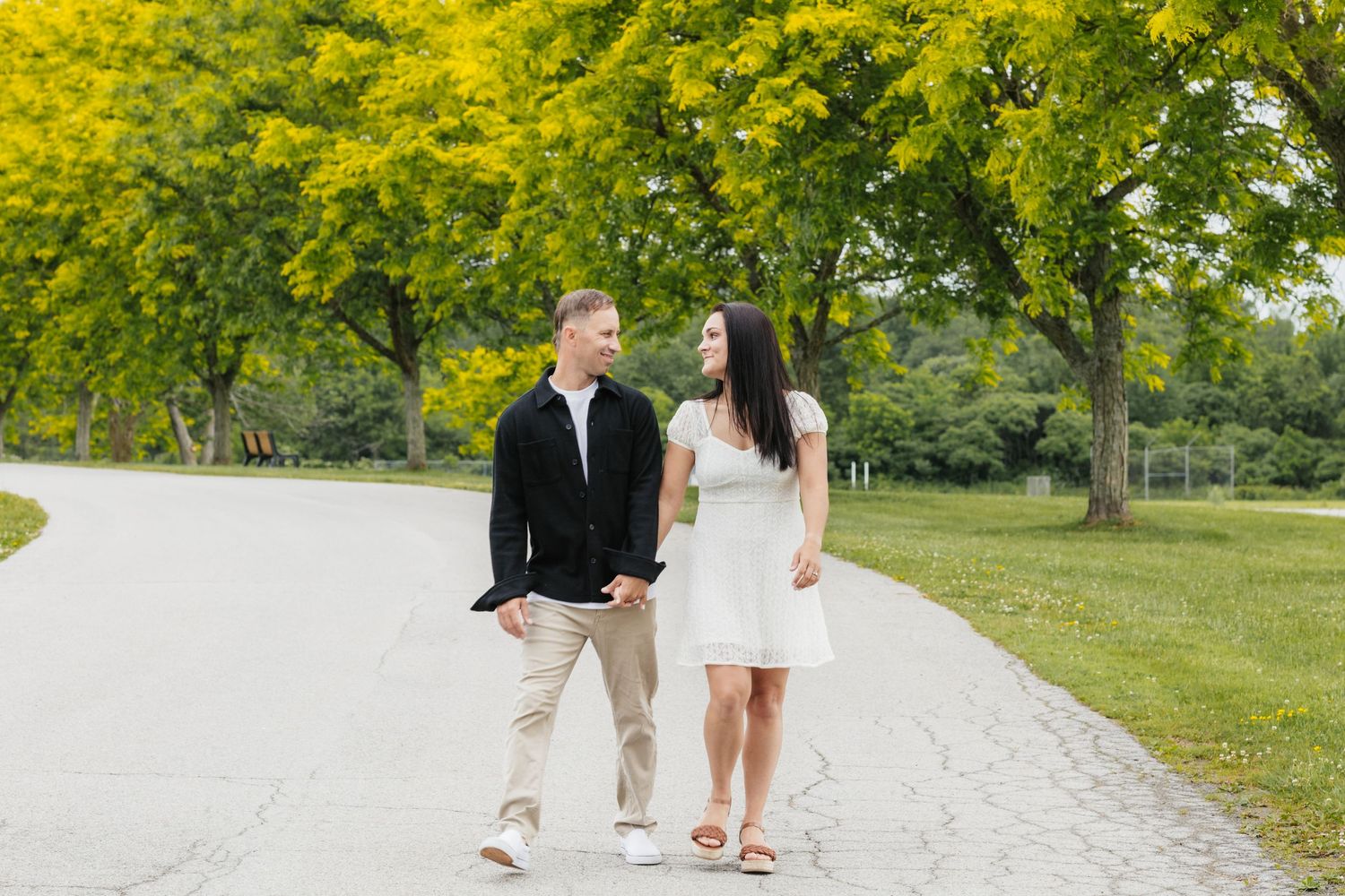 Couple walking on path through park with yellow flowering trees.