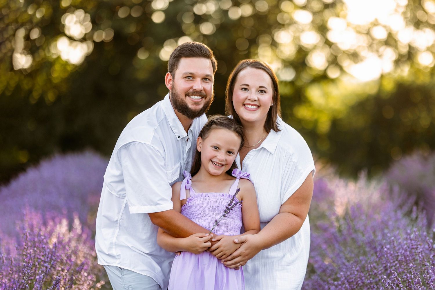 A family poses together in a blooming lavender field during golden hour sunset.  Middle Tennessee Best Family Photographer