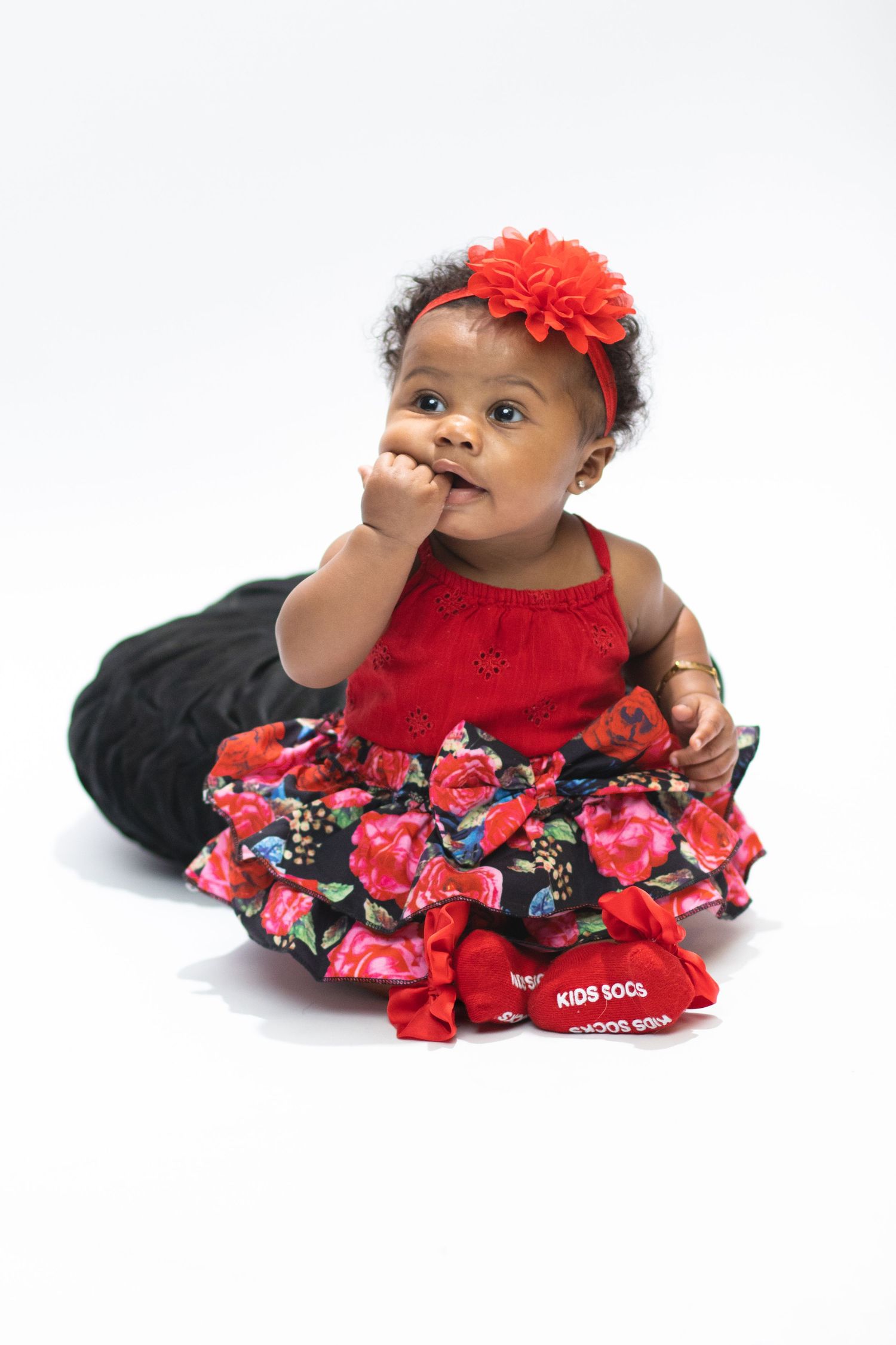 A cute portrait of a baby girl wearing a red floral dress and headband, showcasing children's photography by Empax Studios.