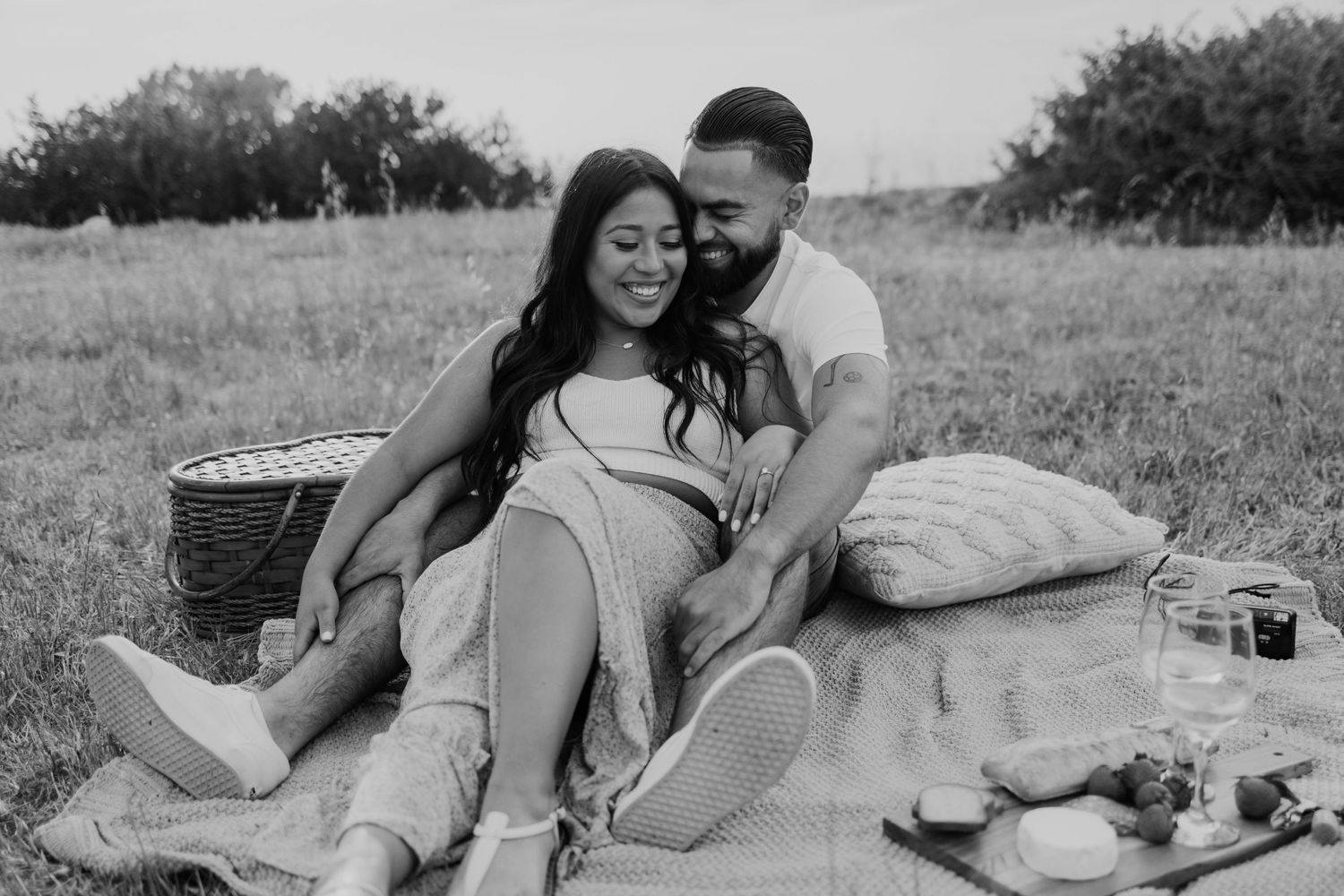 A couple enjoying a picnic on a blanket in a grassy field.