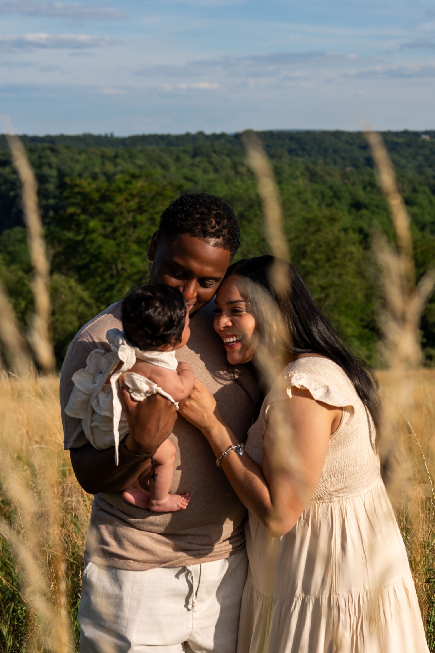 A family shares a joyful moment together in a sunlit field with tall grass.