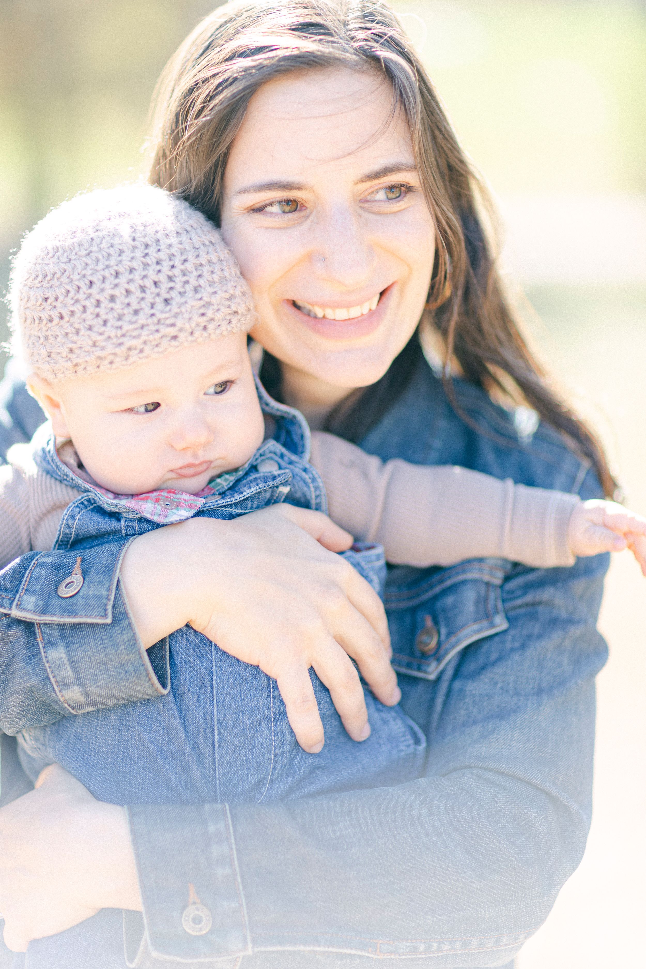 Outdoor portrait showing gentle moment with baby wearing knit bonnet.